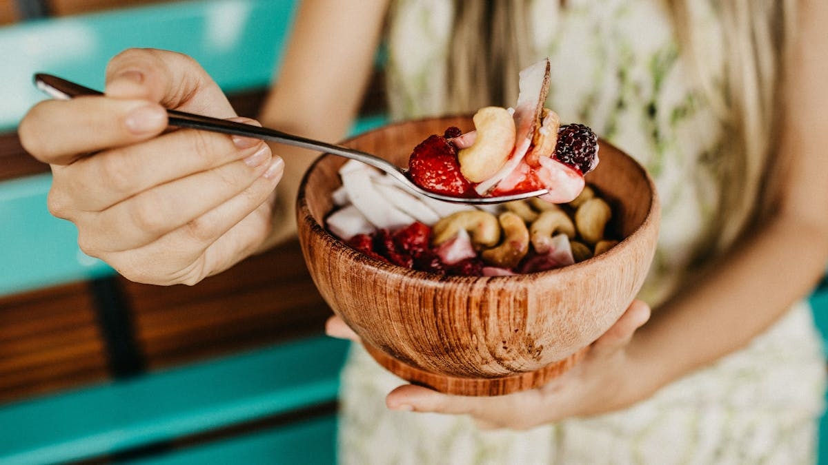 Healthy acai smoothie bowl with fresh berries and nuts held in a wooden bowl.